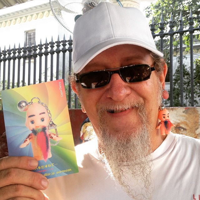 Edesio Alejandro sonriendo con la tarjeta de Cupie Danny, afuera de un edificio colonial en La Habana.