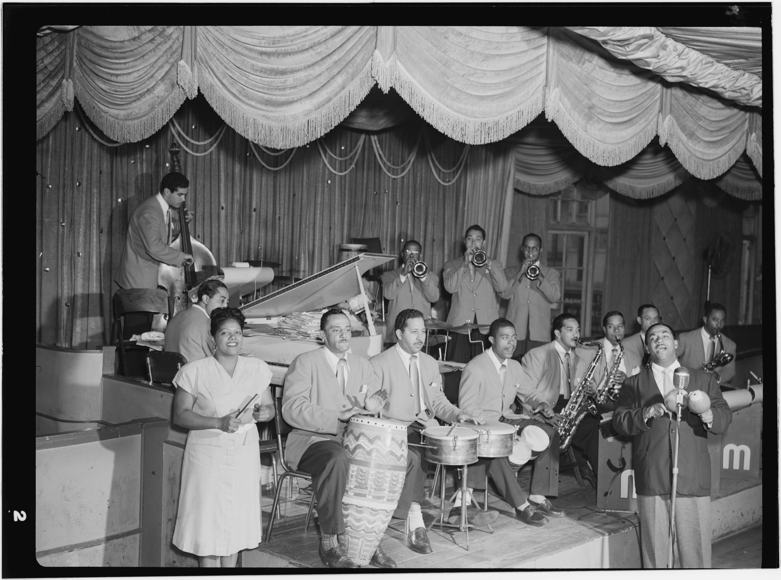 Machito and His Afro-Cubans en el escenario del Glen Island Casino en 1947. Graciela está al frente, a la izquierda; Machito canta al micrófono a la derecha; detrás, la banda completa llena el escenario.